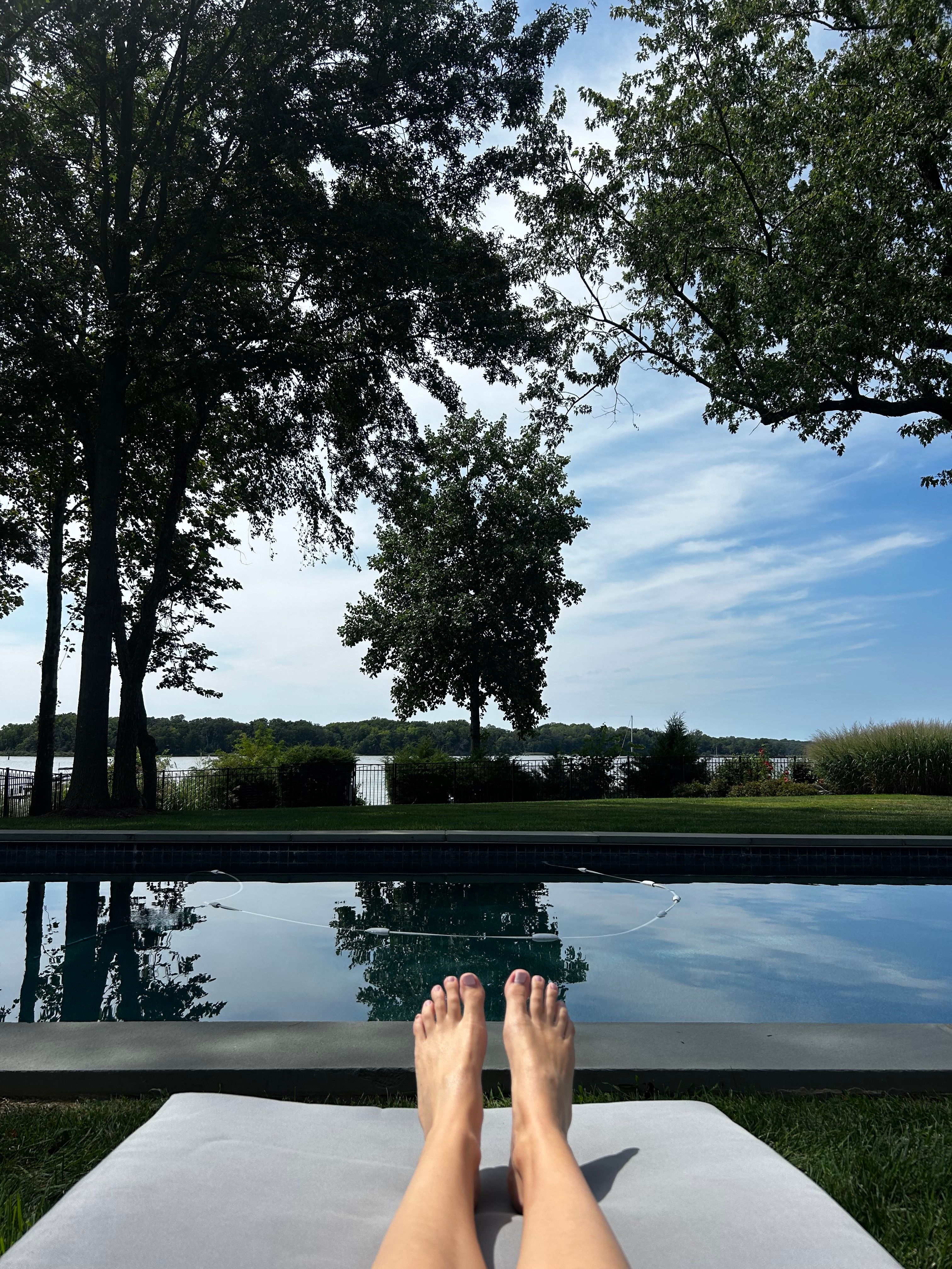 Pool and river from a lounge chair, feet in the foreground