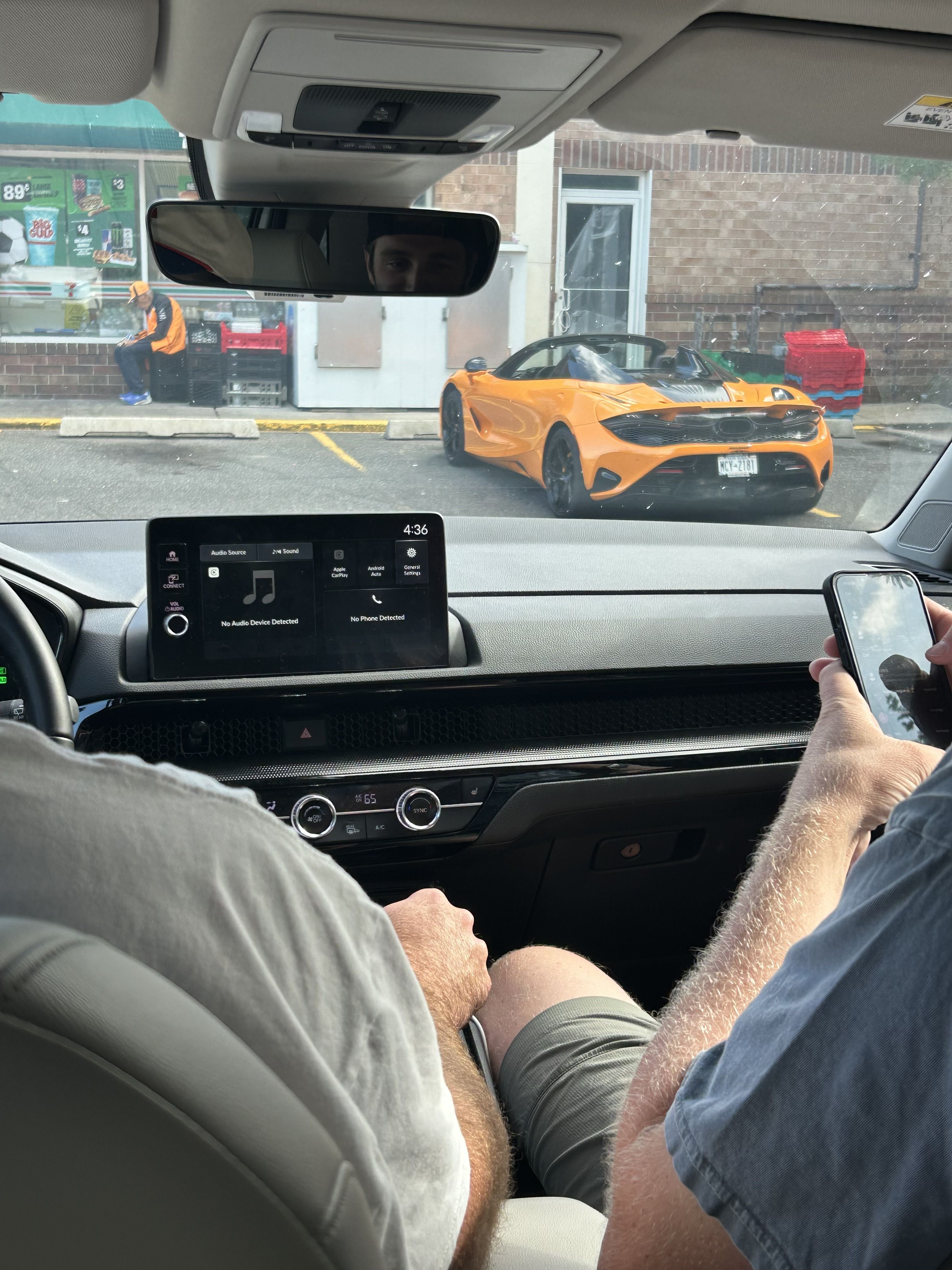 Orange McLaren in a 7-Eleven parking lot, shot from inside a car